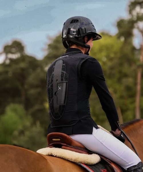E-Twiste-Air-Porté Cavalière de dos portant un gilet airbag équitation Horse Pilot, x In&motion en selle sur un cheval en concours